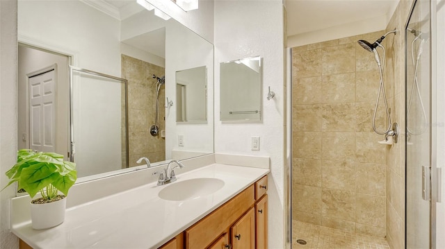 bathroom featuring crown molding, a tile shower, and vanity