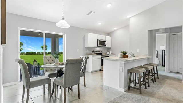 kitchen with white cabinetry, stainless steel appliances, a kitchen breakfast bar, kitchen peninsula, and decorative light fixtures