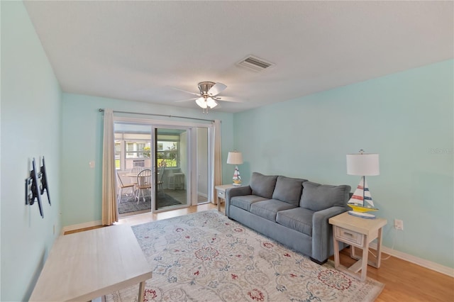 living room with baseboards, ceiling fan, visible vents, and light wood-style floors