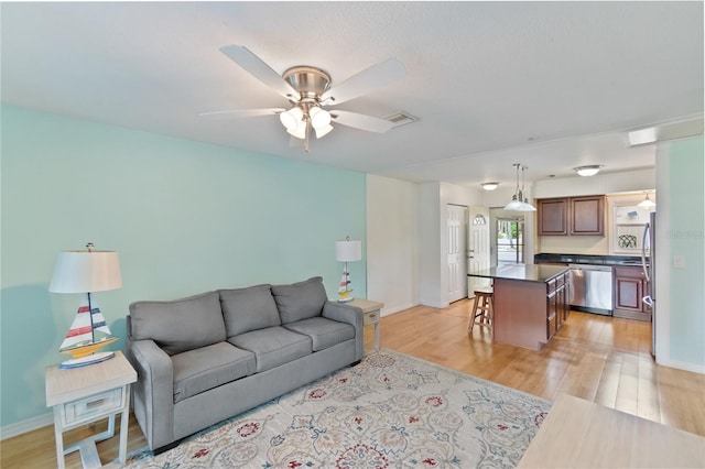 living room featuring visible vents, ceiling fan, light wood-style flooring, and baseboards