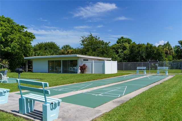 view of home's community featuring fence, a lawn, and shuffleboard