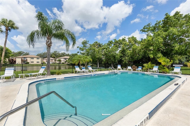 community pool with a patio area and fence