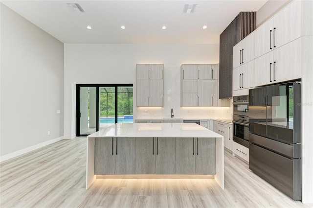 kitchen with light stone counters, a center island, appliances with stainless steel finishes, a kitchen breakfast bar, and light hardwood / wood-style floors