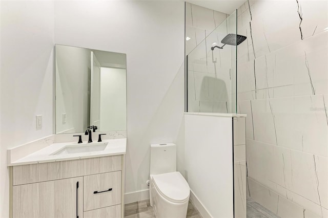 bathroom featuring tiled shower, vanity, and toilet