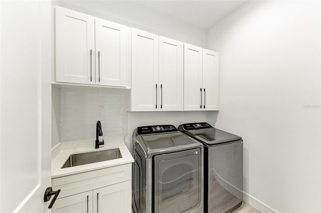 clothes washing area with light hardwood / wood-style floors, sink, cabinets, and independent washer and dryer