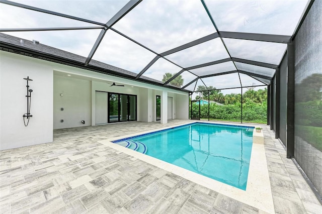 view of pool featuring ceiling fan, glass enclosure, and a patio area