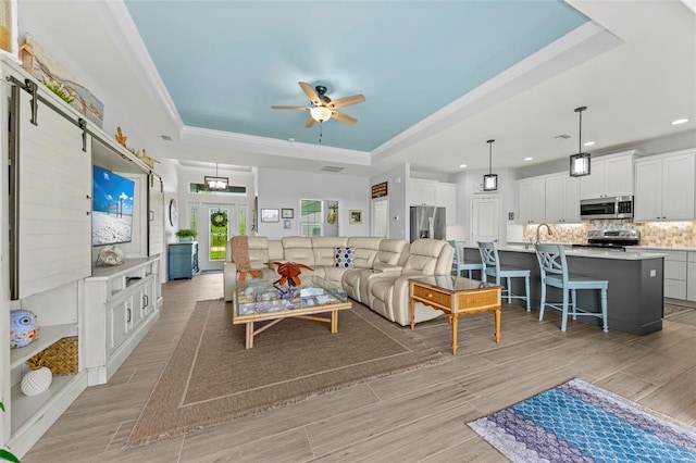 living room featuring ceiling fan, light hardwood / wood-style flooring, and a tray ceiling