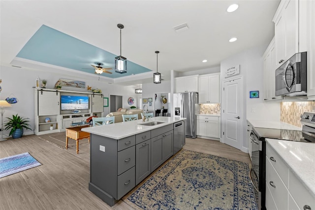 kitchen featuring gray cabinetry, ceiling fan, a center island with sink, white cabinets, and appliances with stainless steel finishes