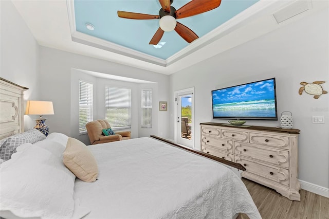 bedroom featuring a raised ceiling, access to exterior, ceiling fan, and hardwood / wood-style flooring