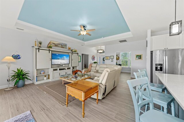 living room featuring a tray ceiling, light hardwood / wood-style flooring, and ceiling fan