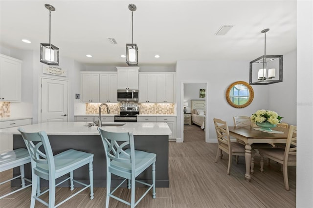 kitchen with appliances with stainless steel finishes, tasteful backsplash, sink, light hardwood / wood-style flooring, and white cabinets