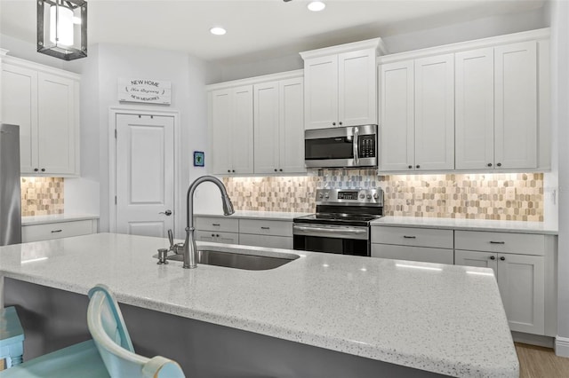 kitchen featuring white cabinetry, sink, stainless steel appliances, and light stone counters