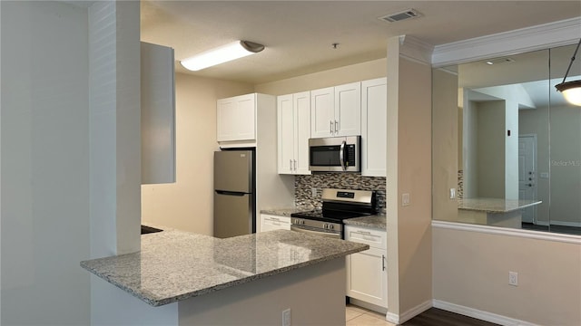 kitchen featuring kitchen peninsula, light stone countertops, stainless steel appliances, and tasteful backsplash