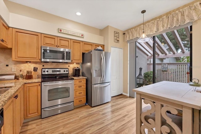 kitchen featuring appliances with stainless steel finishes, hanging light fixtures, light stone countertops, and light hardwood / wood-style floors