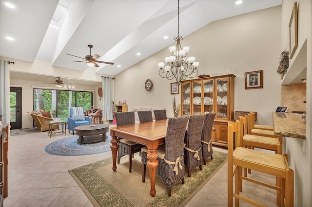 dining room featuring high vaulted ceiling, a skylight, ceiling fan with notable chandelier, and light tile patterned floors