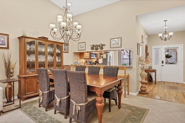 dining room with high vaulted ceiling, a chandelier, and light hardwood / wood-style floors