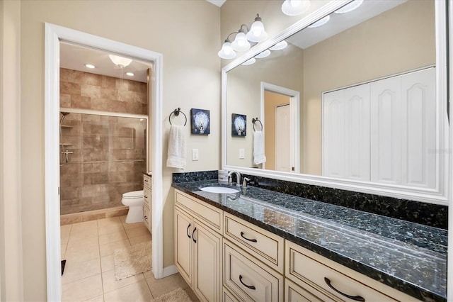 bathroom with vanity, toilet, a shower with shower door, and tile patterned flooring