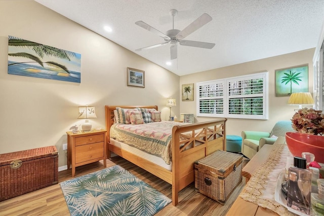 bedroom featuring lofted ceiling, hardwood / wood-style floors, ceiling fan, and a textured ceiling