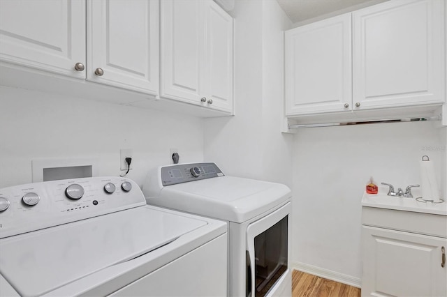 laundry area with cabinets, washer and clothes dryer, and light wood-type flooring