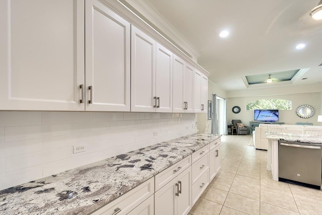 kitchen with white cabinetry, light stone countertops, stainless steel dishwasher, and a tray ceiling