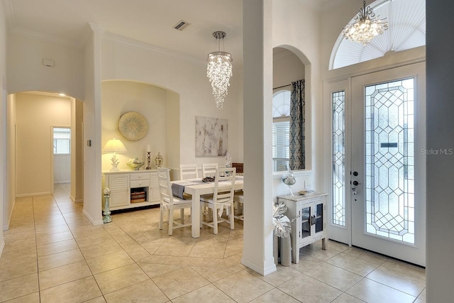 foyer entrance with light tile patterned flooring, crown molding, and a chandelier