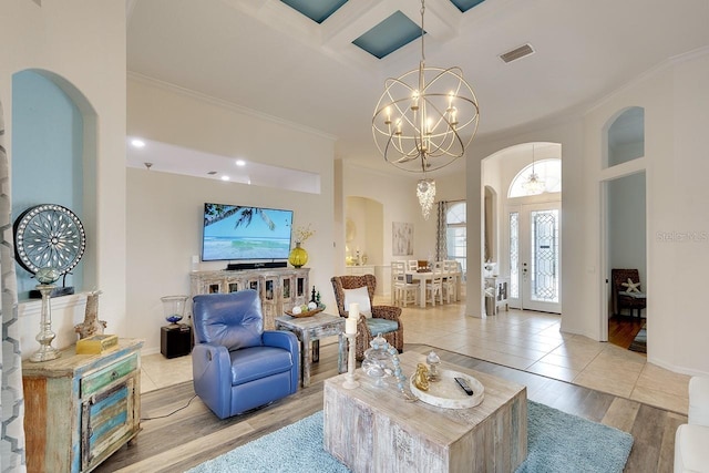 living room featuring crown molding, an inviting chandelier, and coffered ceiling