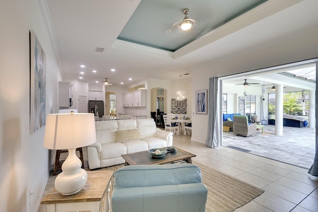 living room with light tile patterned floors, a tray ceiling, and ornamental molding