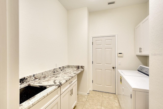 laundry room with washing machine and dryer, cabinets, and light tile patterned floors