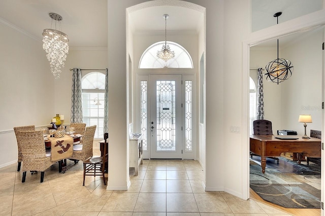 foyer featuring crown molding, arched walkways, baseboards, light tile patterned flooring, and a notable chandelier