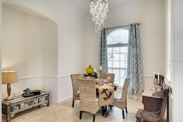 dining area with light tile patterned floors, crown molding, a chandelier, baseboards, and arched walkways