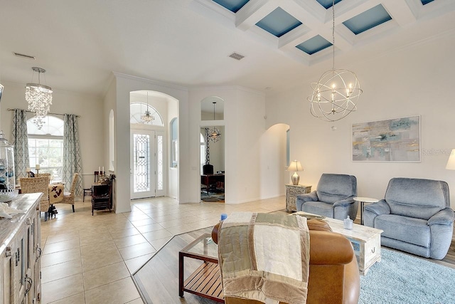 living room featuring arched walkways, coffered ceiling, light tile patterned floors, a notable chandelier, and crown molding