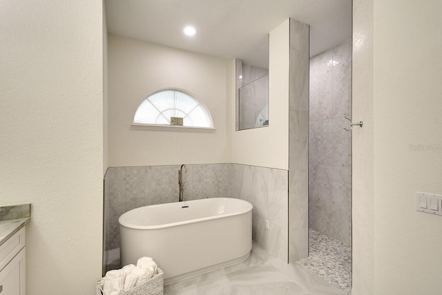 full bath with a freestanding bath, walk in shower, vanity, and marble finish floor