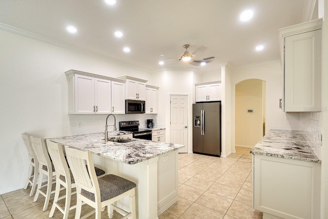 kitchen with ornamental molding, arched walkways, a sink, and appliances with stainless steel finishes