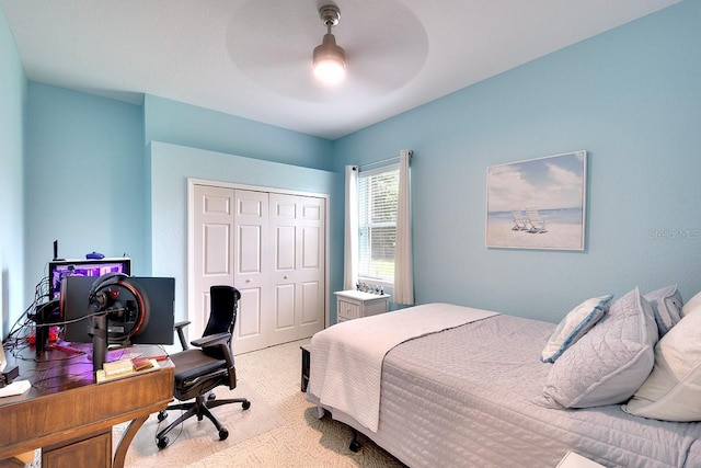 bedroom with ceiling fan, light carpet, and a closet