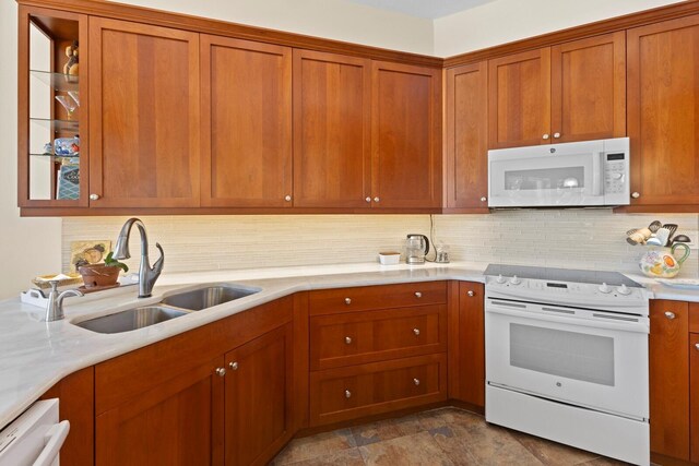 kitchen with decorative backsplash, sink, light stone counters, and white appliances