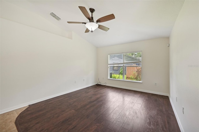 empty room featuring baseboards, visible vents, vaulted ceiling, and wood finished floors