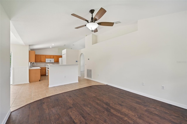 unfurnished living room with ceiling fan, light wood-type flooring, sink, and lofted ceiling