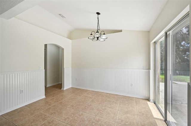 tiled empty room with a notable chandelier, vaulted ceiling, and a wealth of natural light