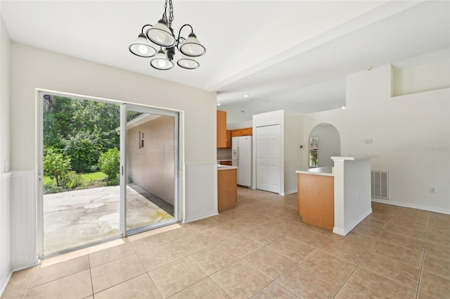 kitchen featuring light tile patterned flooring, a center island, an inviting chandelier, and white fridge with ice dispenser