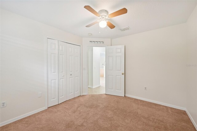 unfurnished bedroom with ceiling fan, a closet, and light colored carpet