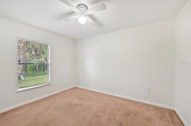 empty room featuring baseboards, ceiling fan, and light colored carpet