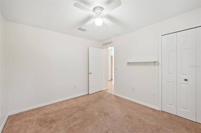 unfurnished bedroom with baseboards, a closet, visible vents, and light colored carpet