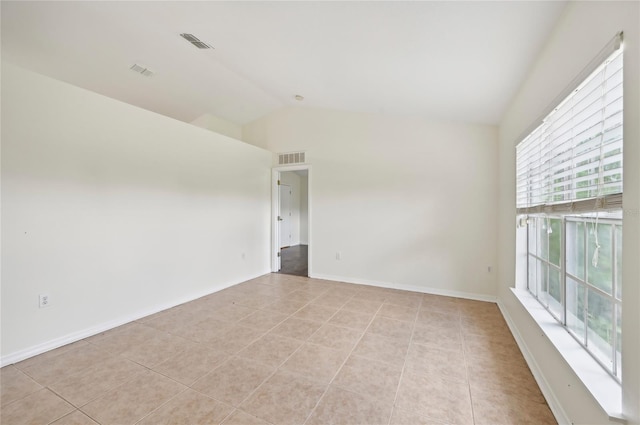 empty room with visible vents, vaulted ceiling, and light tile patterned floors