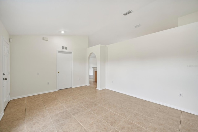 empty room with visible vents, vaulted ceiling, and arched walkways