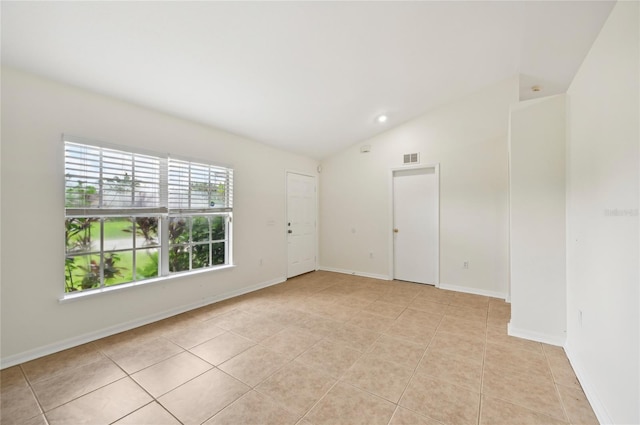 tiled empty room featuring lofted ceiling