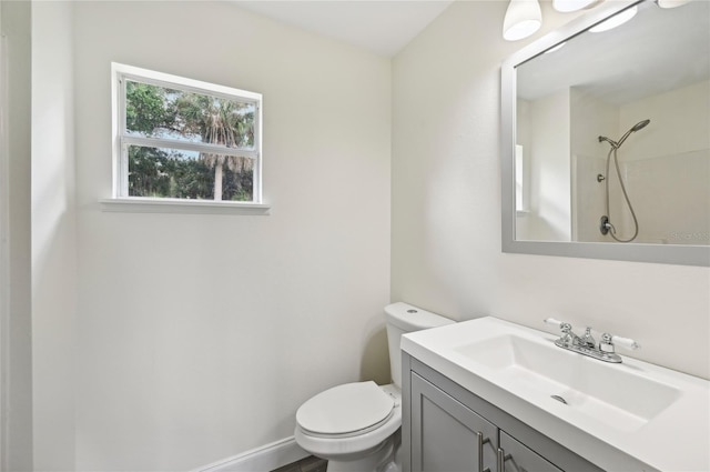 bathroom featuring toilet, walk in shower, vanity, and baseboards