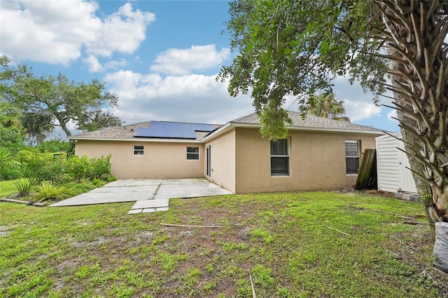 rear view of house with stucco siding, a yard, a storage shed, and a patio