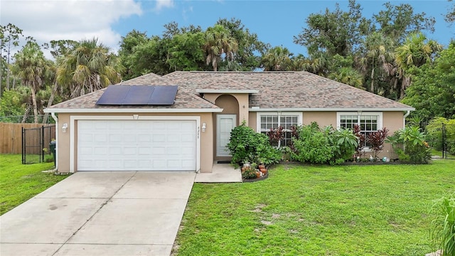 ranch-style house featuring stucco siding, solar panels, concrete driveway, a front yard, and fence