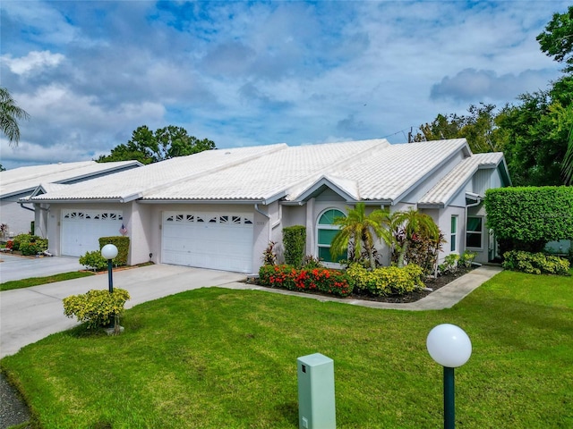 single story home featuring an attached garage, a front lawn, concrete driveway, and stucco siding