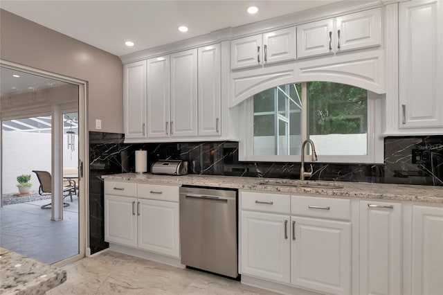 kitchen with white cabinetry, sink, stainless steel dishwasher, and light stone counters